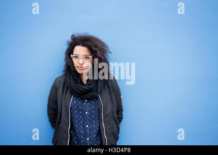 Porträt der selbstbewusste junge Frau stehend vor blauem Hintergrund Stockfoto