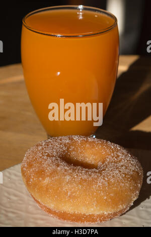 Fried-Donut in weißen Teller und Glas Aprikosensaft Stockfoto