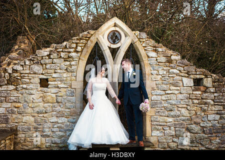 Eine Braut und Bräutigam hand in hand am Tag ihrer Hochzeit in einem Garten. Stockfoto