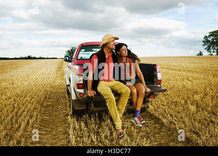 Ein Mann in einem Strohhut und eine Frau sitzen im hinteren Teil ein Pick up Truck. Stockfoto