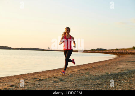 Eine sportliche junge Frau läuft am Strand entlang. Stockfoto