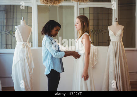 Frau versucht auf Hochzeitskleid mit Hilfe der Mode-designer Stockfoto