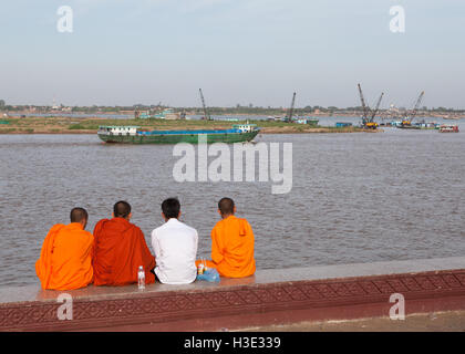 Mönche sitzen auf einer Mauer in der Nähe von Tonle Sap Fluss, Phnom Penh, Kambodscha. Stockfoto