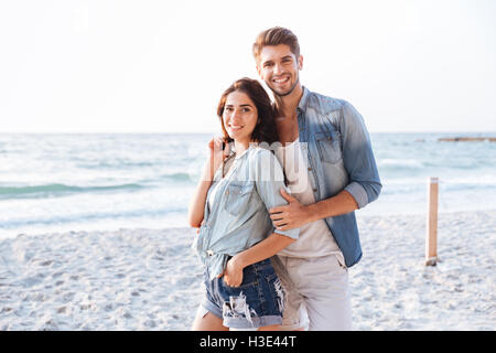 Porträt von schönen jungen Brautpaar stehend und umarmt am Strand Stockfoto