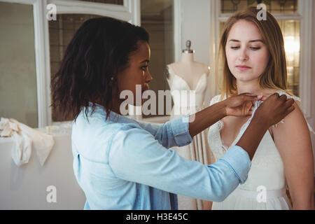 Frau versucht auf Hochzeitskleid mit Hilfe der Mode-designer Stockfoto