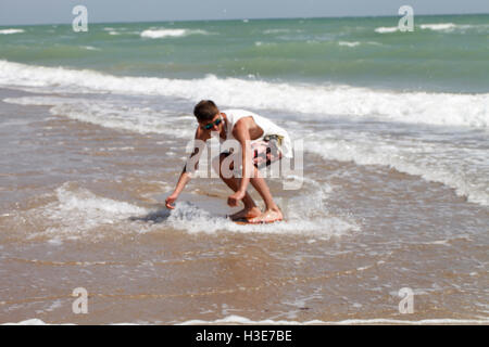 aktive junge Jungs fahren Skimboard an der Küste Stockfoto