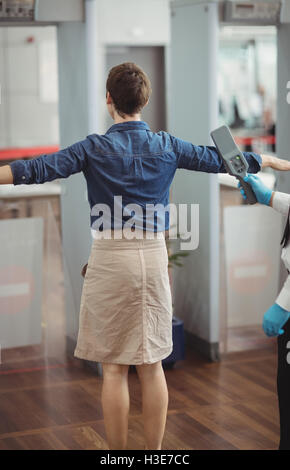 Flughafen Sicherheitsoffizier mit einer Hand hielt Metalldetektor einen Passagier zu überprüfen Stockfoto