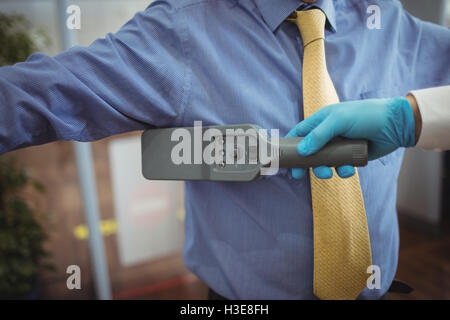 Flughafen Sicherheitsoffizier mit einer Hand hielt Metalldetektor einen Passagier zu überprüfen Stockfoto