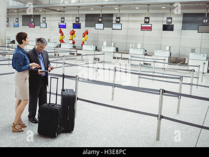 Geschäftsleute warten am Check-in-Schalter mit Gepäck Stockfoto