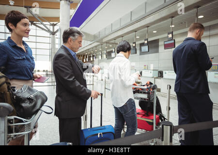 Passagiere warten in der Schlange am Check-in-Schalter mit Gepäck Stockfoto