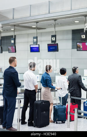 Passagiere warten in der Schlange am Check-in-Schalter mit Gepäck Stockfoto