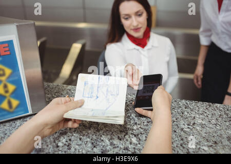 Passagier geben einen Reisepass und ein Handy an einer Fluggesellschaft einchecken Telefonzentrale Stockfoto