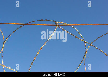 Mauer mit Stacheldraht Klebeband auf blauen Himmelshintergrund Stockfoto