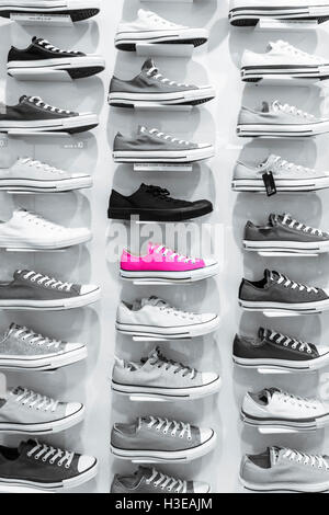 Konzept Bild von einem hellen Rosa deck Schuh mitten in der andere monochrome Schuhe auf einen Shop display Rack stehend Stockfoto
