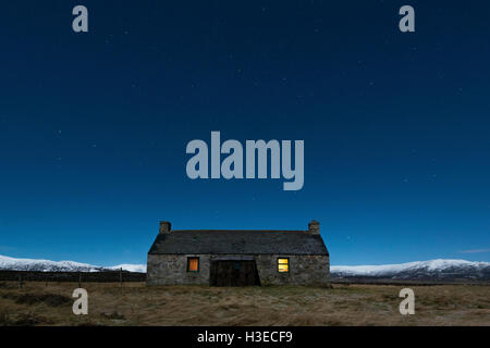 Luibleathann Bothy auf einem kalten Januar Sternenhimmel mit dem warmen Schein von offenem Feuer in das Fenster, in der Nähe von Newtonmore Stockfoto