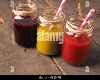 Drei gesunde Smoothies mit Kiwi, rote Beete und Tomaten auf einem rustikalen Holztisch Stockfoto