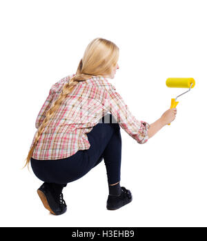 Rückansicht eines Mädchens, das Farbroller malt. Rückansicht Kollektion People. Rückseite Blick auf Person. Isoliert auf weißem Hintergrund. Hockenden Frau malt die Wand-Walze. Stockfoto