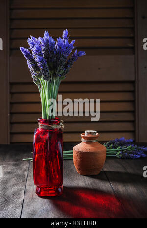 Bündel von Lavendelblüten in Retro-Vase und Keramik Topf mit Öl auf alten hölzernen Hintergrund Stockfoto