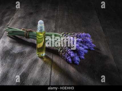 frische Lavendelblüten und ätherische Öle als natürliche Aromatherapie für Kopfschmerzen und Migräne Relief auf alten hölzernen Hintergrund Stockfoto