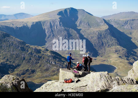 Männer lernen Klettern auf einem Felsen auf Tryfan mit Blick auf Y Garn zu Fels als Kulisse in den Bergen von Snowdonia National Park (Eryri). Ogwen Wales UK Stockfoto