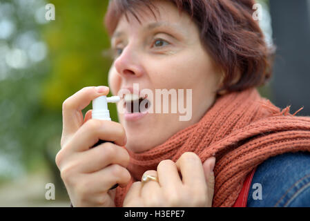 Junge Frau mit Hals-Spray in der kalten Jahreszeit Stockfoto