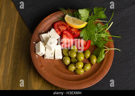 Feta-Käse, Tomaten, Oliven und Kräutern in einer Ton-Platte - griechischen Mittagessen Stockfoto