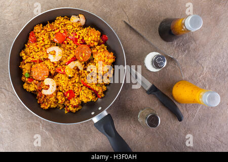 Frische Chorizo, Huhn und King prawn Paella in einem Topf auf einem Stein Arbeitsplatte mit verschiedenen Gewürzen Stockfoto