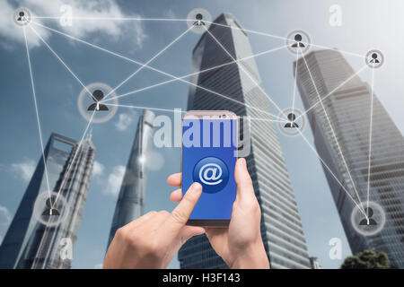 Hand halten Smartphone und Klick auf Button mit at-Zeichen mit Menschen Symbole verbunden. E-Mail-Marketing, Newsletter und Bulk Mail con Stockfoto