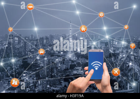 Hand mit Smartphone mit Tokyo City Scape und Wifi-Netzwerk-Verbindung. Smart-City-Netzwerk-Verbindung-Konzept Stockfoto