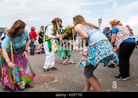 Frauen, die beide von Morris Seiten und Mitglieder der Öffentlichkeit, tanzen die 'gun Dance" mit hölzernen Stäben als Waffen, während auf Broadstairs Harbour Jetty. Stockfoto