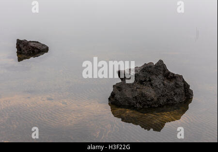 Lavagestein und Sand Muster aus gelben und schwarzen Lava und vulkanischen Sand am Strand im Wasser. Stockfoto