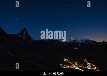 Luftaufnahme von Breuil Cervinia Dorf Leuchten in der Nacht, die berühmten Skigebiet im Aostatal, Italien. Wunderbaren Sternenhimmel über Stockfoto