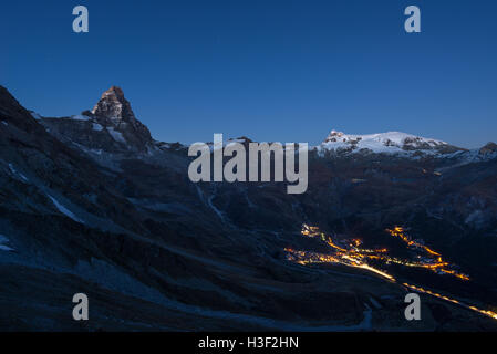 Luftaufnahme von Breuil Cervinia Dorf Leuchten in der Nacht, die berühmten Skigebiet im Aostatal, Italien. Wunderbaren Sternenhimmel über Stockfoto