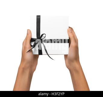 Isolierte Frauenhände halten Weihnachtsgeschenk White Box mit Band auf weißem Hintergrund. Hand reichen und die Präsentationsbox öffnen. Stockfoto