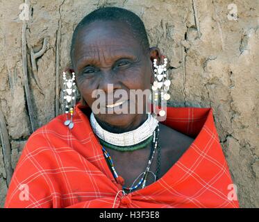 Nahaufnahme von Masai Seniorin tragen traditionelle rote Decke und komplizierte handgefertigte Perlen Schmuck vor Lehmhütte Stockfoto