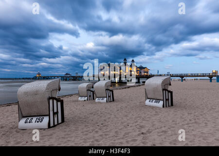 Liegestühle vor dem beleuchteten Pier der Ostsee Ostseebad Sellin, Rügen, in der Dämmerung Stockfoto