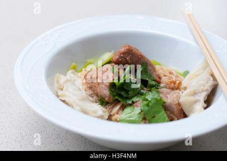 Eiernudeln mit köstlich geschmortes Schweinefleisch und Knödel in weiße Schüssel. Stockfoto