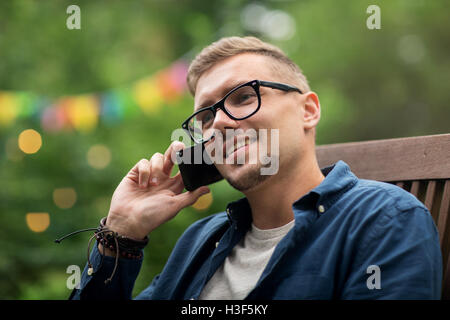 Man fordert Smartphone auf Sommer-Gartenparty Stockfoto