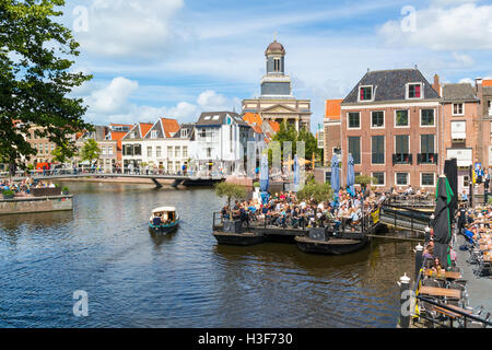 Hartebrugkerk Kirchturm, Boot und Menschen auf der Terrasse des Cafés am Rhein-Kanal in Leiden, Südholland, Niederlande Stockfoto