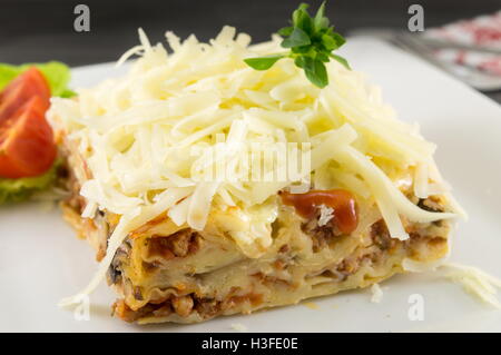 Lasagne-Teil mit frischem Gemüse auf einem Teller serviert Stockfoto
