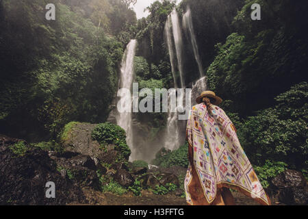 Rückansicht Schuss weibliche Touristen zu Fuß in Richtung Wasserfall im Regenwald. Junge Frau im Urlaub in der Natur. Stockfoto