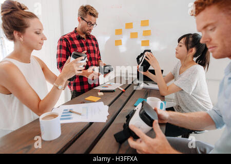 Gruppe von jungen Entwicklern arbeitet an der Verbesserung augmented Reality-Geräte. Verschiedene Business-Team im Tagungsraum betrachten virtu Stockfoto