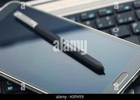 Phablet mit Stift auf Laptop-Tastatur. Stockfoto