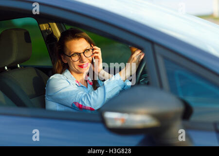 Geschäftsfrau Multitasking während der Fahrt, Kaffee trinken und reden am Telefon Stockfoto