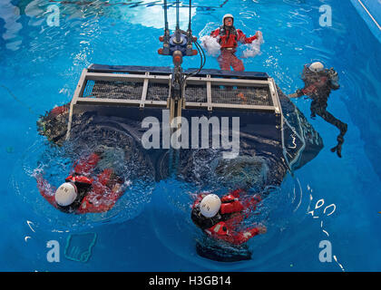 Bremerhaven, Deutschland. 30. September 2016. Teilnehmer einer Klasse beenden eine mock Offshore-Helikopter-Cockpit nach seiner Untertauchen in der Ausbildungs-Pool von Falck-Sicherheitsdienstleistungen in Bremerhaven, Deutschland, 30. September 2016. Rescue Diver sichern Bereich, wie sie die Passagiere aussteigen sehen. Personen, die im Offshore-Bereich arbeiten lernen, wie man nach einem Rettungshubschrauber Wasserlandung während der sogenannten "Hubschrauber Unterwasser Escape Training" (HUET) überleben. Foto: INGO WAGNER/Dpa/Alamy Live News Stockfoto