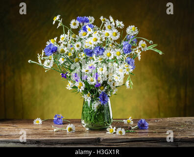 Bouquet von Kamillen und Kornblumen in der Vase auf dem Holztisch. Stockfoto