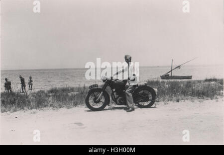 Unidentifizierter britischer Mann auf einem Matchlosen Motorrad G3L mit einem ägyptischen Felucca-Segelboot mit ägyptischen Fischern im Hintergrund um 1952. Foto aufgenommen in Ismailia, in der Nähe des Großen Bitteren Sees Stockfoto