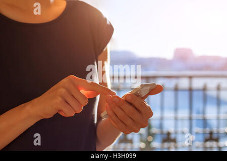 Junge Frau mit einem Smartphone bei Sonnenuntergang Stockfoto