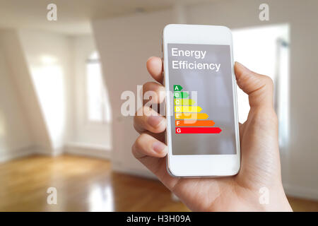 Energieeffizienzklasse auf Smartphone-app von Frau Immobilienmakler und Wohngebäude im Hintergrund Stockfoto