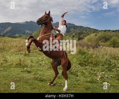 Kasachen Pferd Reiter mit erhobenem Arm auf Aufzucht Wallach in Hunnen Dorf Kasachstan Stockfoto